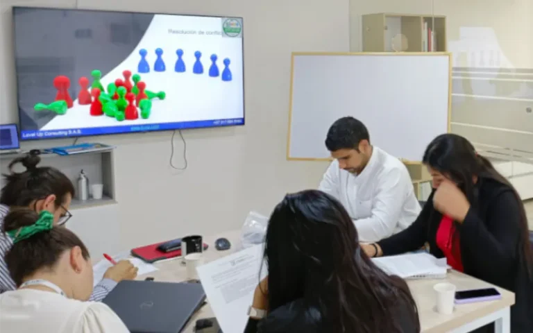 Grupo de personas realizando un taller frente una pantalla que muestra una fichas de colores - Taller de habilidades negociación